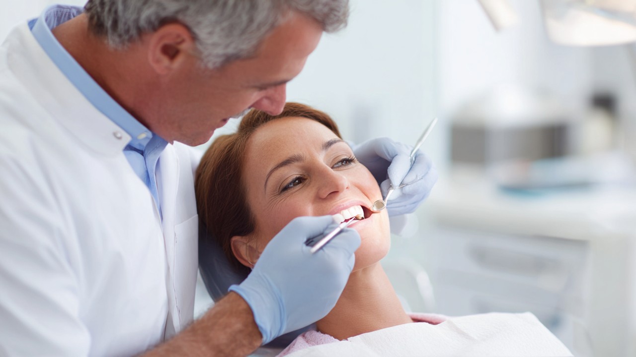 Dentist carefully bonding dental veneers onto patient's teeth in a bright, clean dental clinic with professional instruments.