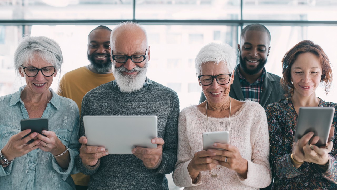 Diverse group of international patients using smartphones, tablets, and laptops to access healthcare website at home, expressing satisfaction.