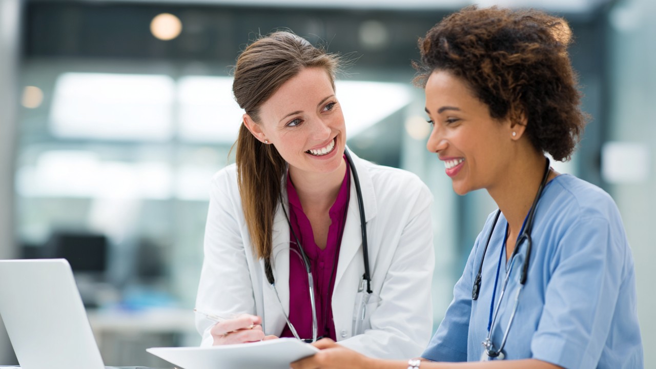 Friendly healthcare professional consulting with bariatric patient in a modern clinic, reviewing medical charts with smiles in a welcoming environment.