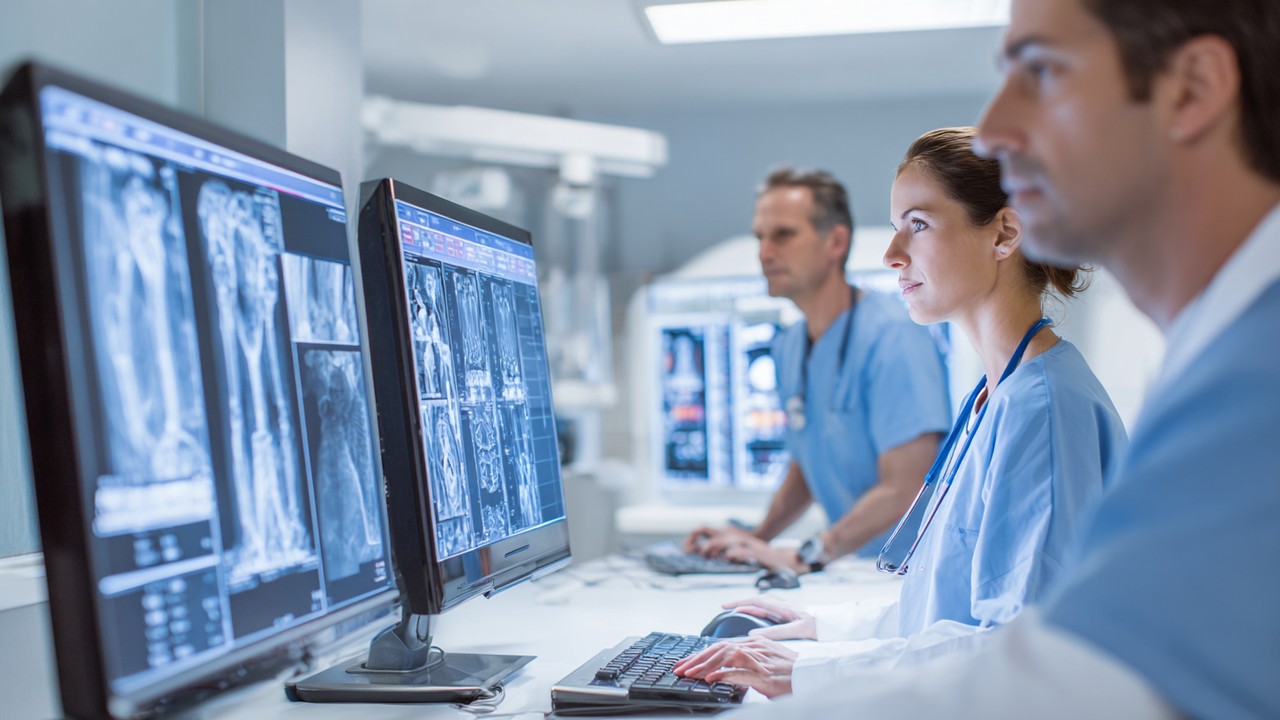 Doktor perubatan menilai imbasan MRI dan CT tulang dan sendi pada skrin digital dalam persekitaran klinik yang profesional dan tenang.
