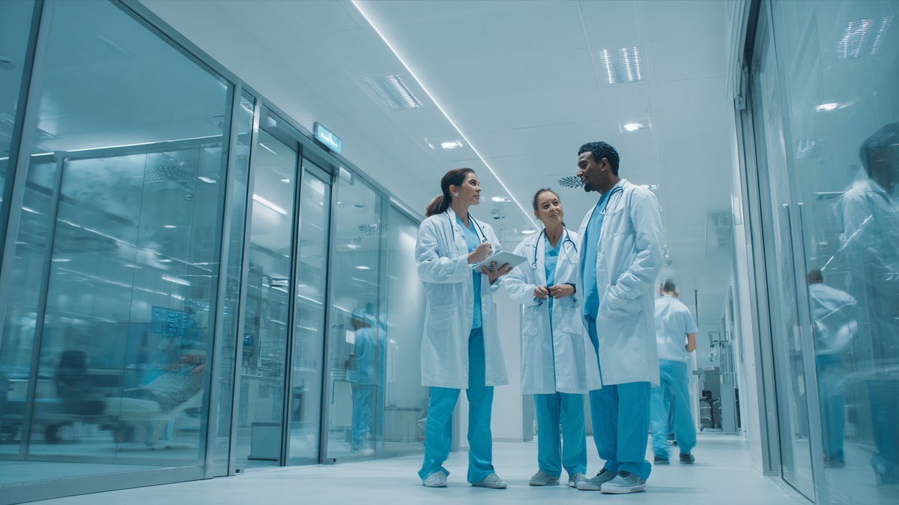 Modern hospital oncology department with diverse doctors and nurses consulting over cancer treatment plans in a bright, clinical environment.