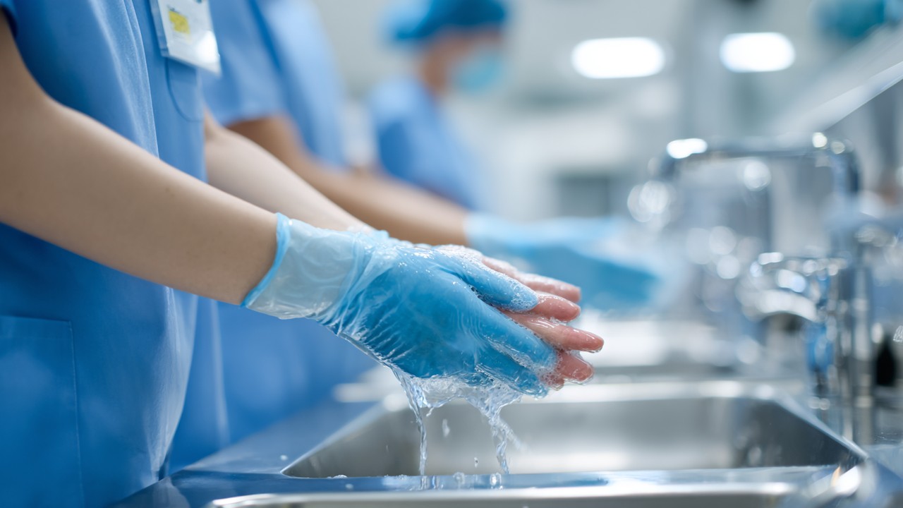 Staf ortopedik bedah mencuci tangan dengan sabun dan air di hospital, menekankan kebersihan dan pencegahan infeksi.