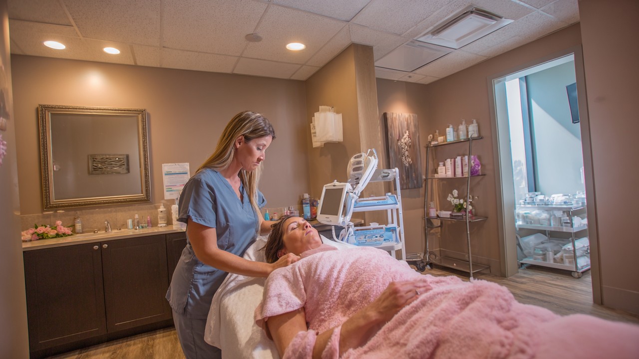 Serene recovery room in a cosmetic care center with a person resting comfortably, healthcare professionals providing attentive support in a calm environment.