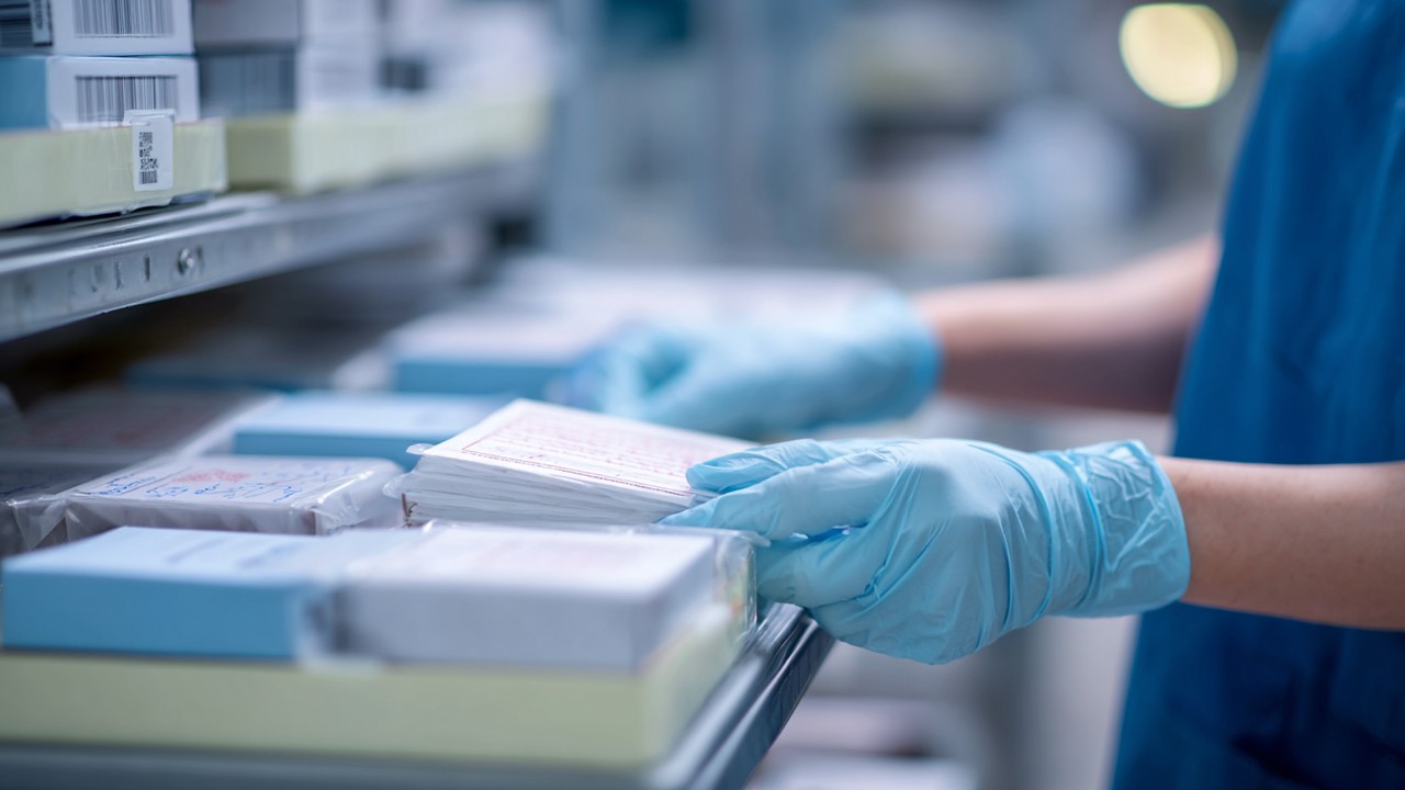 Close-up of a healthcare professional reviewing orthopedic implant packaging and documentation in a sterile hospital storage area, emphasizing implant traceability and safety protocols.