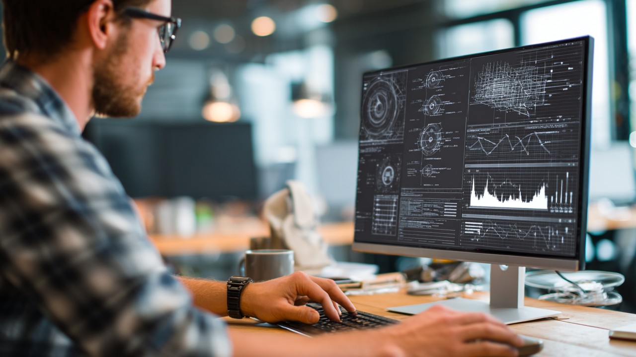 Close-up of a professional web developer working on website optimization with technical diagrams and performance analytics on a computer screen in a modern office.