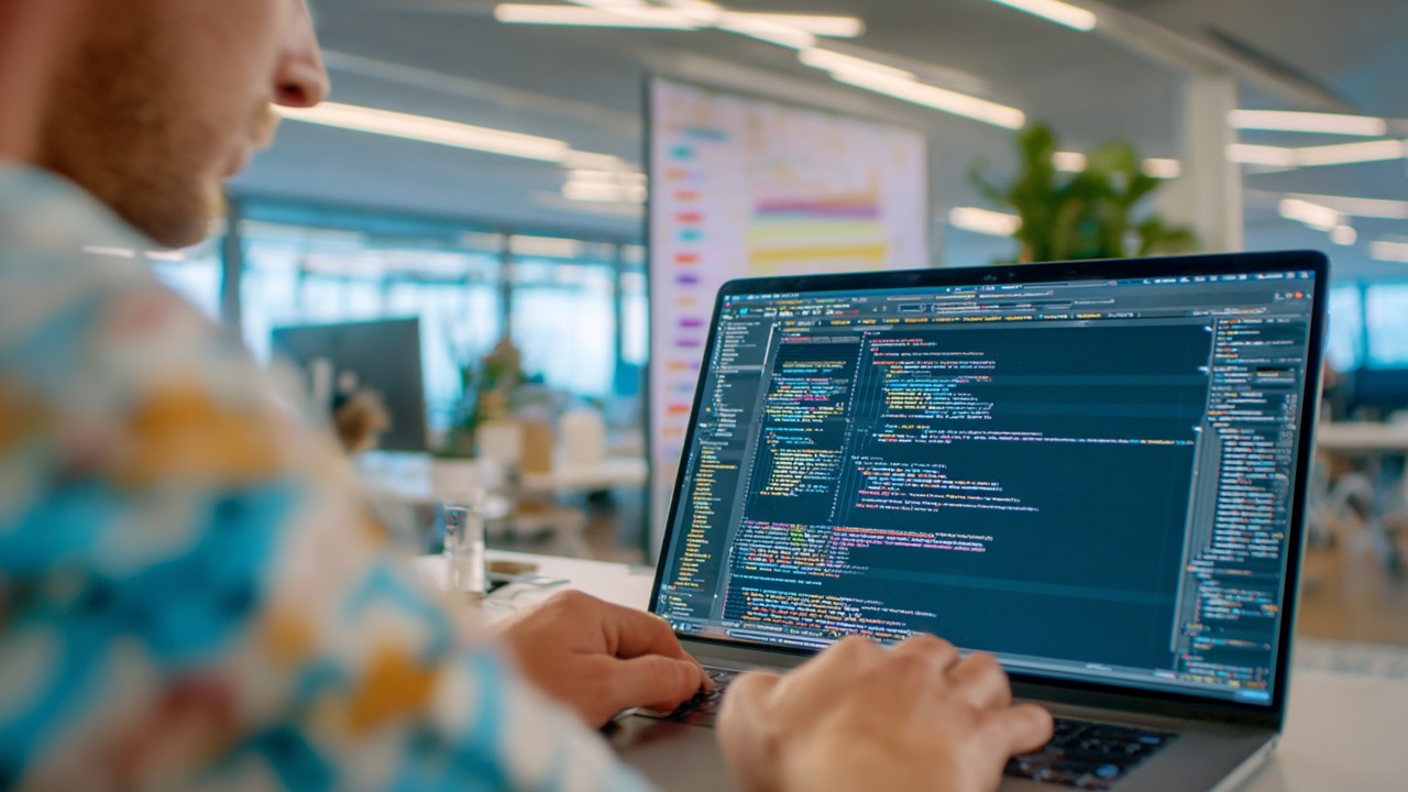 Close-up of a web developer working on a laptop with code focused on SEO elements like hreflang tags, in a modern office with SEO strategy charts.