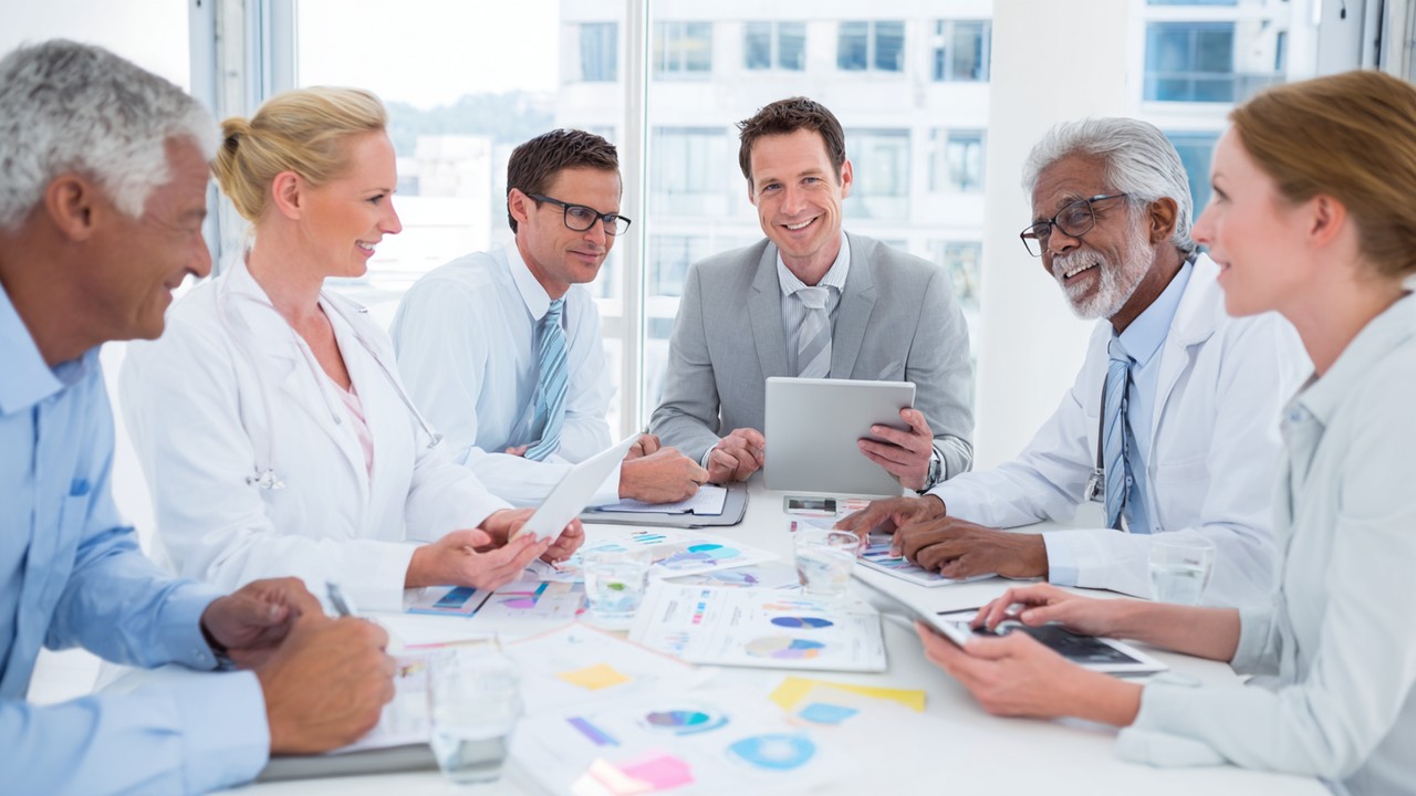 Diverse international patients and healthcare coordinator reviewing medical travel care packages with digital tablets in a bright, organized office.