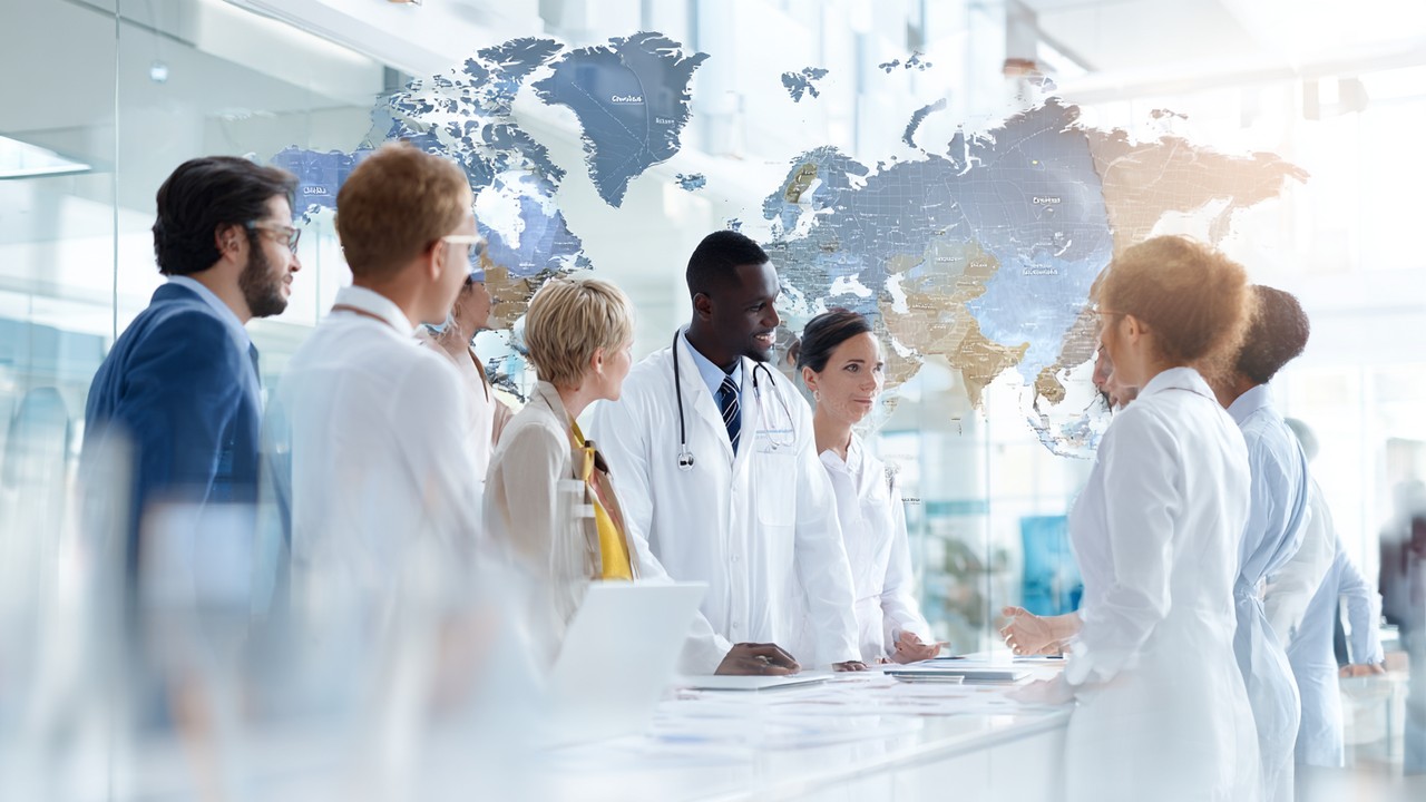 Diverse international patients consulting a medical travel advisor in a modern office with maps and brochures, illustrating global medical tourism planning.