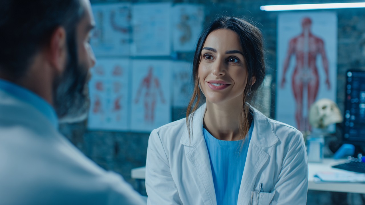 Medical professional explaining rhinoplasty recovery timeline to patient in modern clinic with anatomical nose models and medical charts.