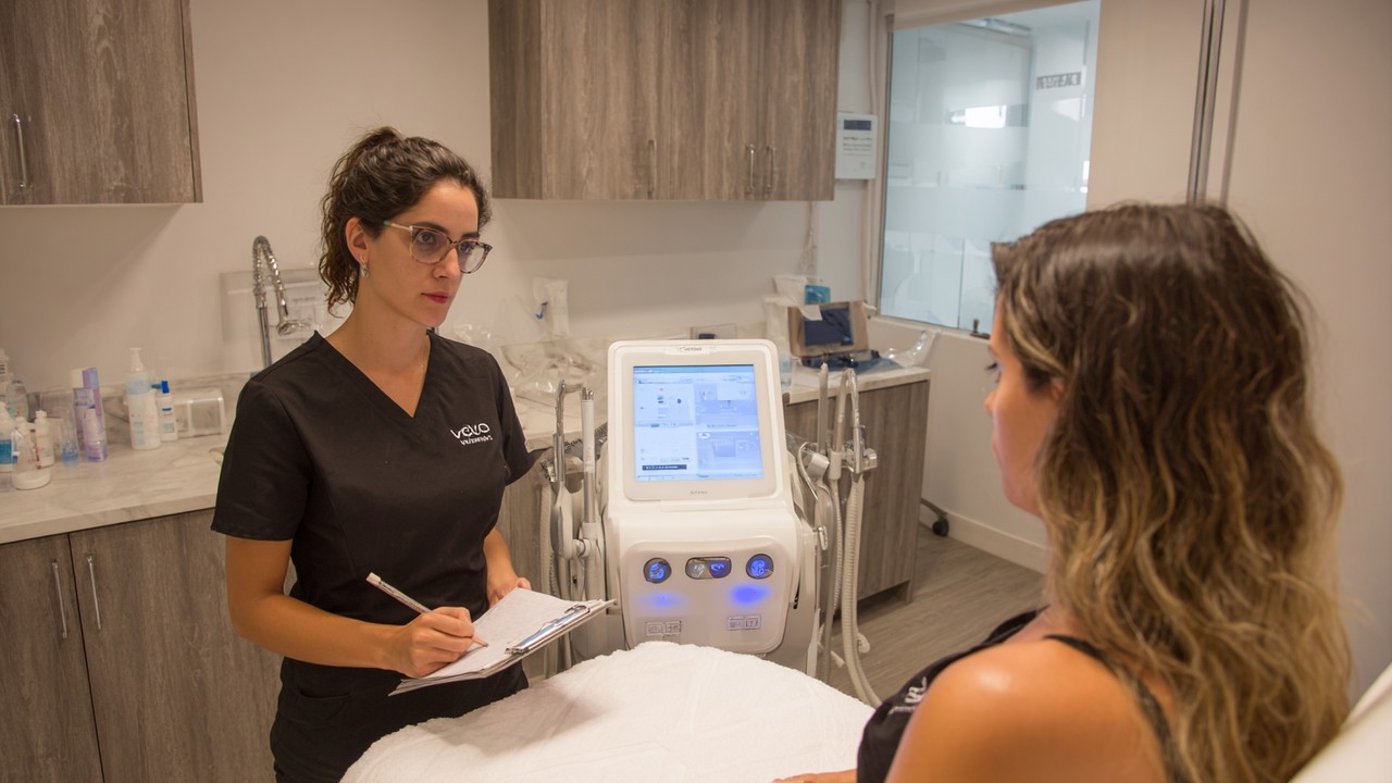 عيادة تجميل حديثة في البرازيل مع أخصائي محترف يستشير مريضًا في بيئة طبية متطورة وهادئة، مع معدات متقدمة.