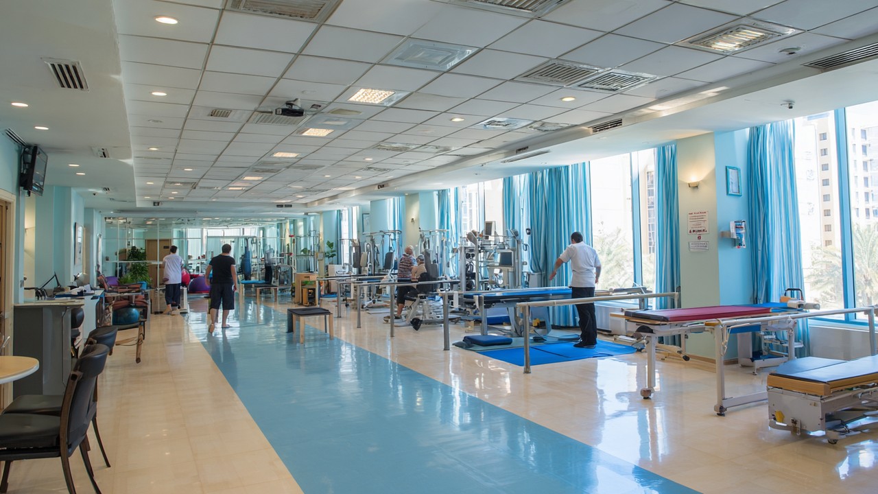 Moderní rehabilitační oddělení v jordánské nemocnici s pacienty při fyzioterapii, světlé prostředí a lékařské vybavení.
