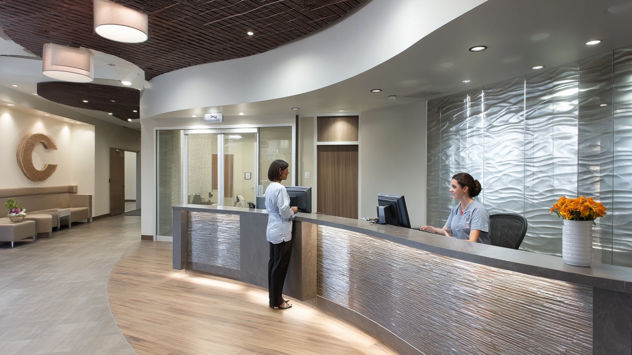 Modern magánrákkezelő központ recepciója, betegkoordinátor segít egy páciensnek, korszerű orvosi technológia és kényelmes környezet.