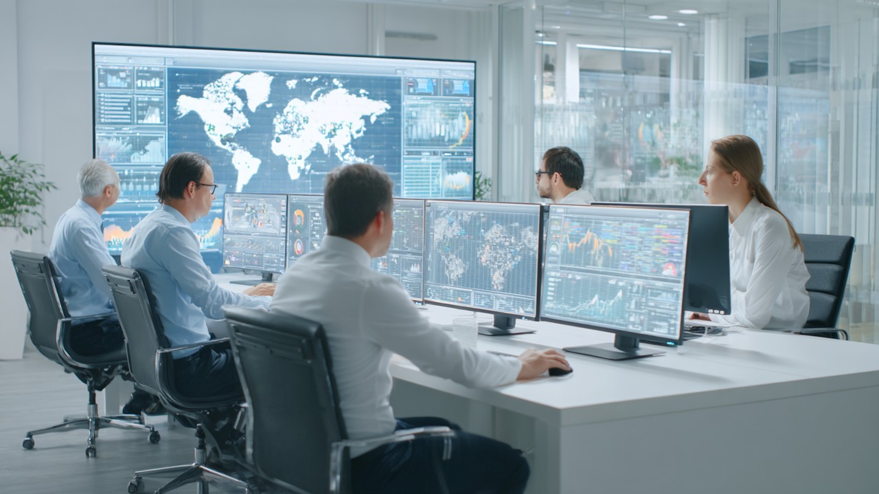 Professional team analyzing global demographic data and website analytics on multiple screens for medical tourism market research.