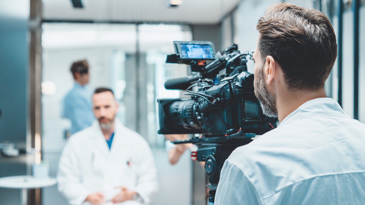 Professional videographer filming a patient consultation and hair transplant procedure in a modern clinical setting, capturing detailed shots.