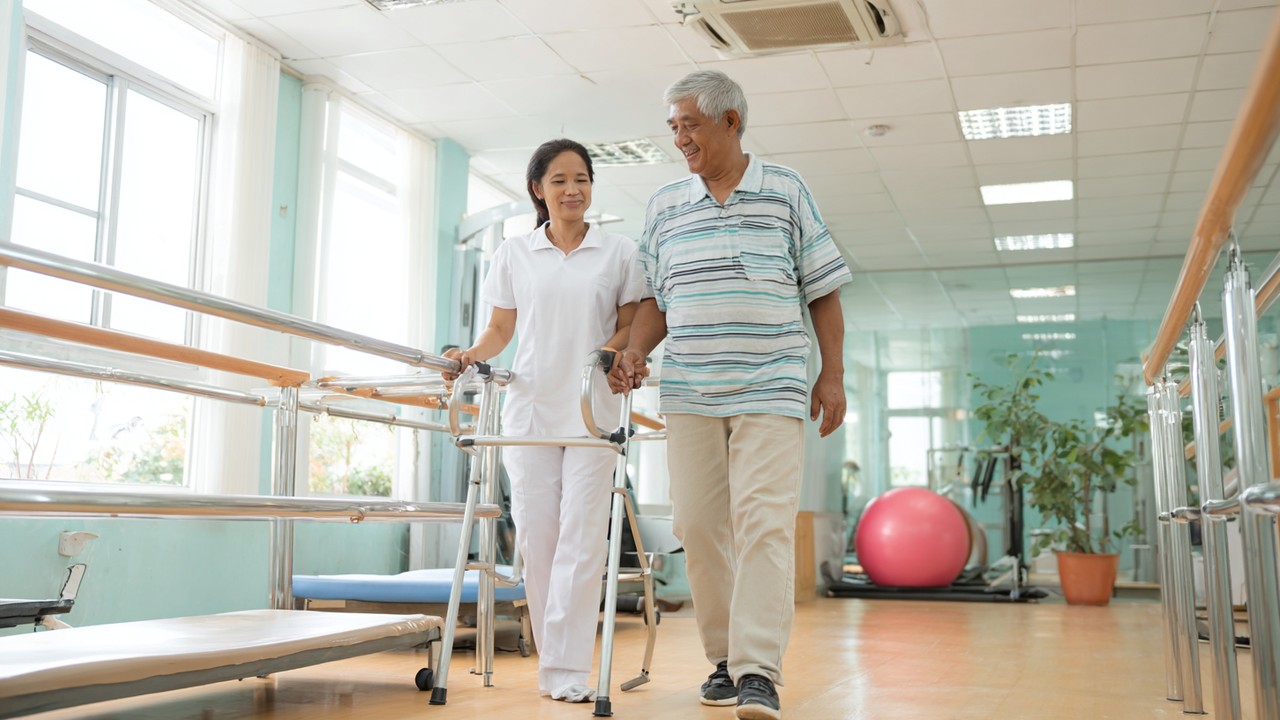 Senior Filipino patient performing assisted hip rehabilitation exercises with a physical therapist in a bright Philippine hospital therapy room, promoting recovery and mobility.