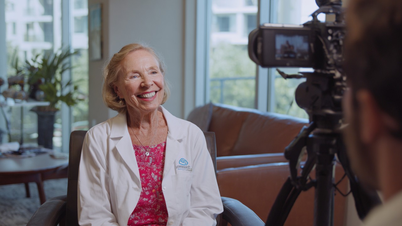 Smiling patient sharing healthcare experience during a testimonial video recording in a bright medical clinic, emphasizing trust and patient engagement.