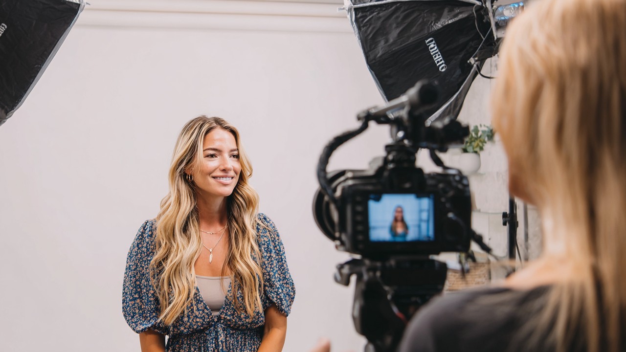 Social media influencer filming a beauty and wellness video in a bright studio, showcasing hair restoration results with professional lighting.